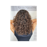 Nahaufnahme von krausem, gesund gepflegtem Haar mit glänzenden, definierten Locken – sichtbar mit Feuchtigkeit versorgt und frizzfrei gestylt.