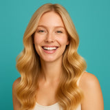 Lächelnde blonde Frau mit gesunden, glänzenden Haaren vor türkisfarbenem Hintergrund – inspiriert vom Look der Marke Moroccanoil.